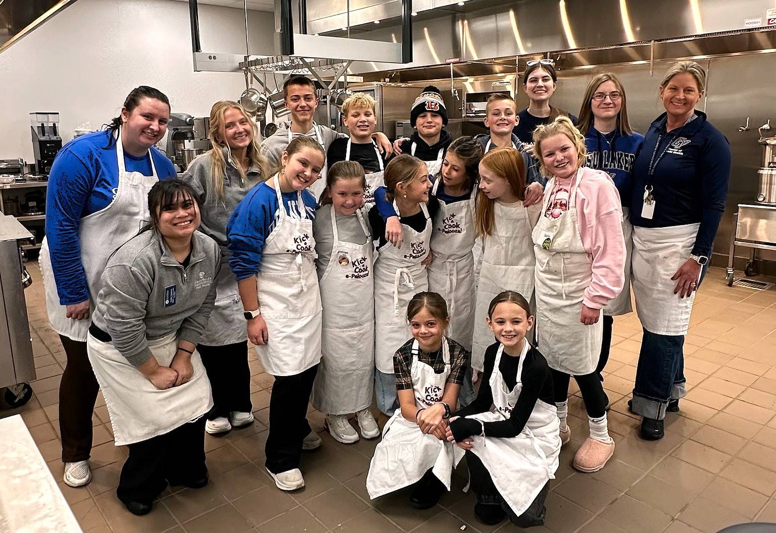MPH Program Director, Dr. Ranelle Brew, along with MPH students and children participating in the Healthy Kids Culinary Academy pose for a group photo in GVSU's Culinary Kitchen Lab.